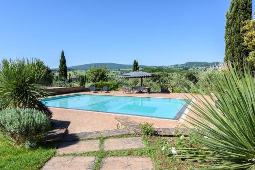 StradaVilla San Gimignano View的花园内的游泳池配有桌子和遮阳伞