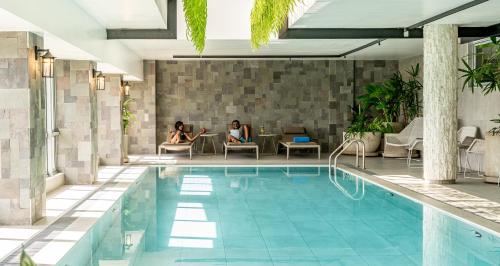 内罗毕Dusit Princess Hotel Residences Nairobi的两个女人坐在游泳池旁边的桌子上