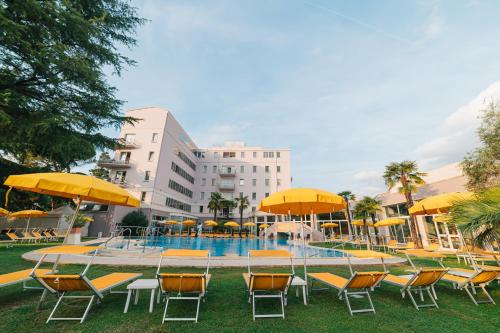 阿巴诺泰尔梅海尔维温泉酒店的大楼前的带椅子和遮阳伞的游泳池