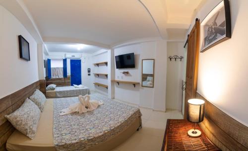 伦索伊斯Pousada Nativos Lençois的小房间设有两张床和电视