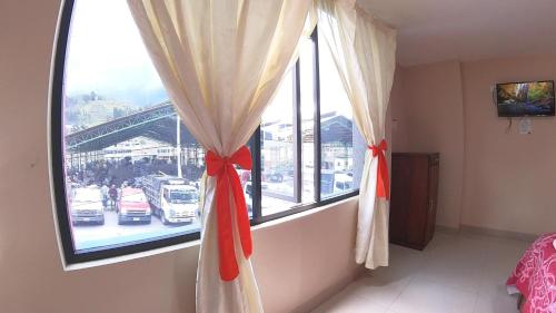GuamoteHostal Flor de los Ángeles的客房设有带红色弓的窗帘的窗户。