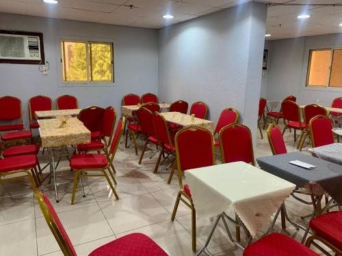 麦加Najmat Alnoor Almaabdah Hotel的用餐室配有桌椅和红色椅子