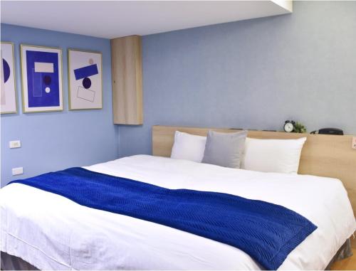 台中市塔木德酒店Choice 台中公园馆的一间卧室配有一张带蓝色墙壁的大床
