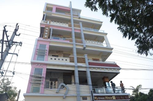 蒂鲁帕蒂SBHS Neeladri Homestay的一座高大的粉红色建筑,阳台上有人