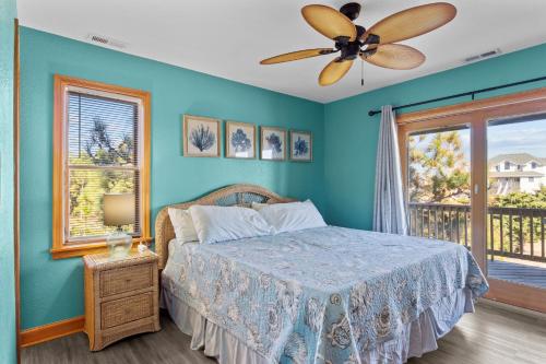 Waves7150 - Fintastic Waves by Resort Realty的一间带蓝色墙壁的卧室和一张带风扇的床