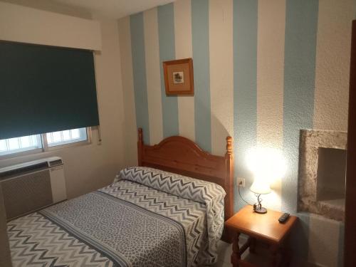 特鲁希略Hostal Trujillo的一间小卧室,配有一张床和一张带台灯的桌子