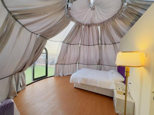 HunaywahDesert Safari Dubai Over Night Stay的一间卧室设有天蓬、一张床和一个窗口