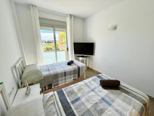 圣安东尼奥·德·卡隆NEW! Apartamento con 2 piscinas, parque infantil, a 1 min de la playa的客房设有两张床、一台电视和一扇窗户。