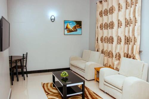 多多马Mesuma Hotel Dodoma的客厅配有2张白色沙发和1张桌子