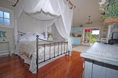 WaimaukuFreshwaterfarm Cottages - Muriwai的一间卧室配有一张带天蓬的床
