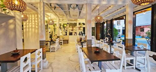 南圣胡安Casa Oro Eco Hostel的配有木桌和白色椅子的餐厅
