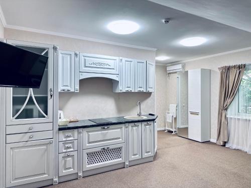 克洛佩夫尼茨基Hotel Korona的厨房配有白色橱柜和平面电视。