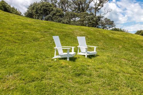欧尼罗亚莫瑞斯公寓套房酒店的两把白色椅子坐在草地山顶上
