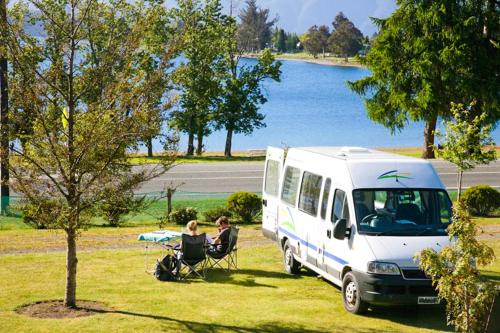 蒂阿瑙Te Anau Lakeview Holiday Park & Motels的一对夫妇坐在白色面包车旁边的椅子上