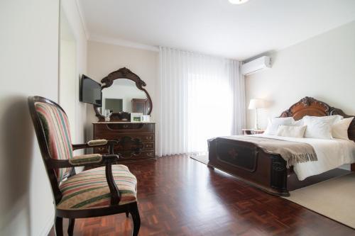 蓬塔德尔加达Casa Cecilia Meireles的一间卧室配有一张床、一把椅子和镜子