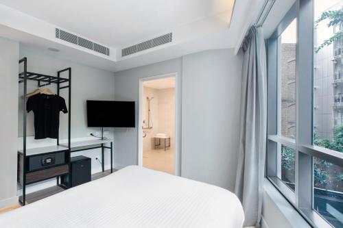 悉尼Kith Hotel Darling Harbour的一间卧室设有一张床、一台电视和一个窗口。
