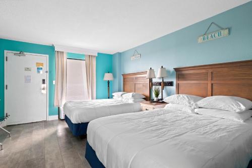 默特尔比奇Oceanfront Oasis的两张位于酒店客房的床,拥有蓝色的墙壁