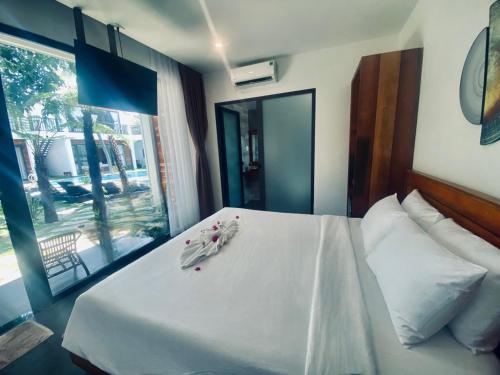 美奈Tuong Vy Boutique Hotel Mui Ne的一间卧室配有一张带白色床单的床和一扇窗户。