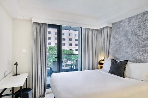 悉尼Kith Hotel Darling Harbour的配有一张床、一张书桌和一扇窗户的酒店客房