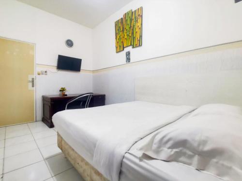 雅加达Kartini Residence RedPartner的卧室配有一张白色大床和一张书桌