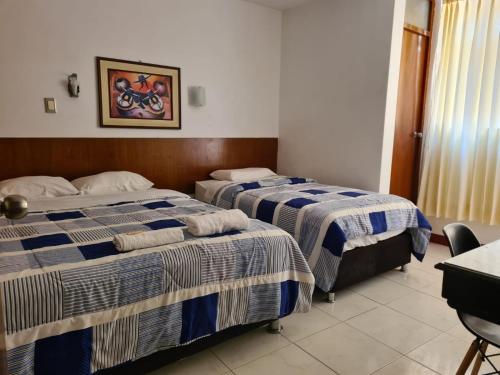 齐克拉约Hotel Esmeralda的酒店客房设有两张床和一张桌子。