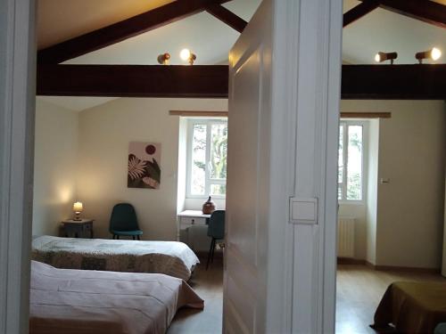 莱瑟佩瑟Les Trois Geais的一间卧室配有两张床、一张桌子和两个窗户。