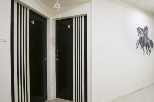 巴罗达OYO Hotel Shiv Kunj的一间设有黑色门的房间,墙上挂着马