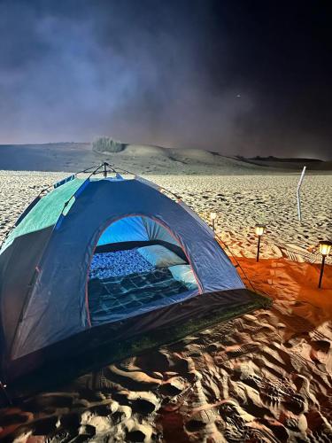 HunaywahDubai Tourism and Travel Services的沙漠中沙子上的蓝色帐篷