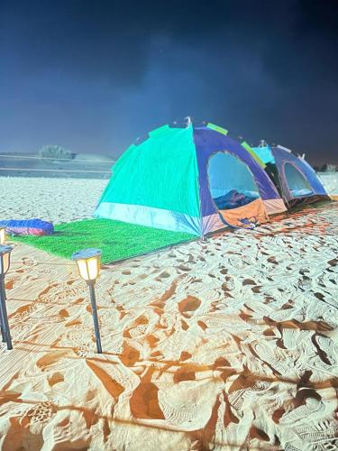 HunaywahDubai Tourism and Travel Services的两顶帐篷位于海边的沙滩上