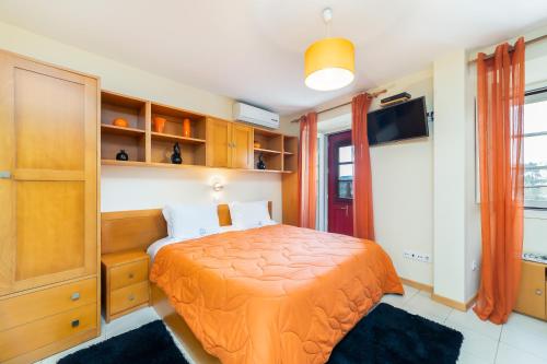 科英布拉欢乐之家的一间卧室配有一张带橙色床罩的床