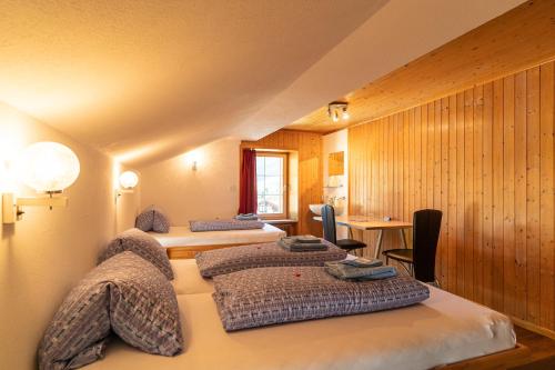 瓦尔斯雪绒花宾馆的客房设有三张床、一张桌子和一张书桌