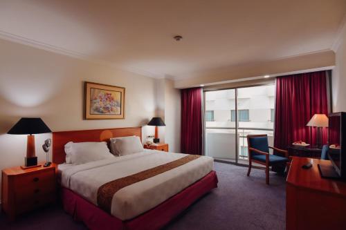 泗水Surabaya Suites Hotel Powered by Archipelago的一间设有大床和窗户的酒店客房
