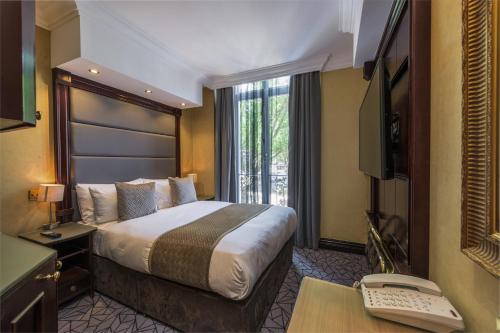 伦敦Hyde Park International的酒店客房配有一张床和一张带电脑的书桌