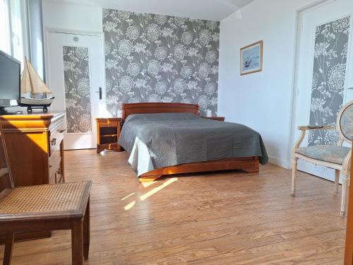 滨海图维列La fleur du soleil的卧室配有1张床、1张桌子和1把椅子