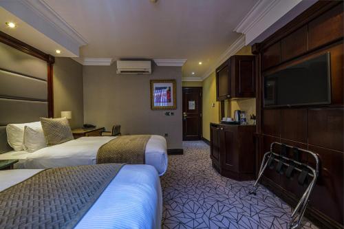 伦敦Hyde Park International的酒店客房设有两张床和一台平面电视。