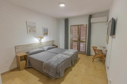 科尼尔-德拉弗龙特拉Hotel Tres Jotas Conil的卧室配有1张床、1张桌子和1把椅子