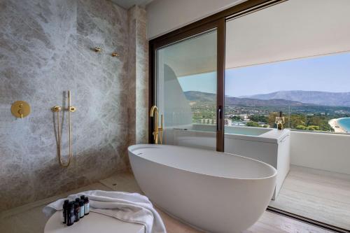 圣塞多罗伊Isla Brown Corinthia Resort & Spa, Curio Collection by Hilton的带浴缸的浴室和大窗户
