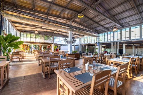 芭东海滩Karon Island Boat Boutique Hotel的餐厅设有木桌、椅子和窗户。