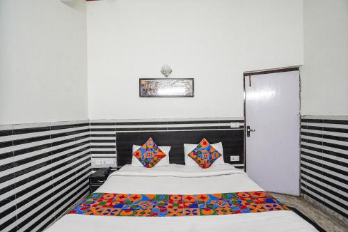 阿格拉FabHotel Sarwan的一间卧室配有一张带色彩缤纷枕头的大床