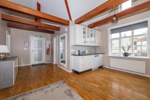 胡萨维克Bjarnabúð的一间铺有木地板的大厨房,配有白色的橱柜