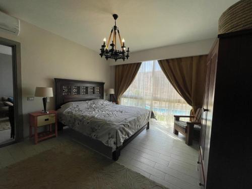 艾因苏赫纳Beautiful chalet in Il Monte Galala المونت جلالة ch15-01-01的一间卧室配有一张床、一个吊灯和一扇窗户