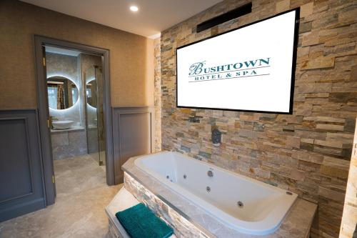 科尔雷恩Bushtown Hotel & Spa的带浴缸的浴室和墙上的电视