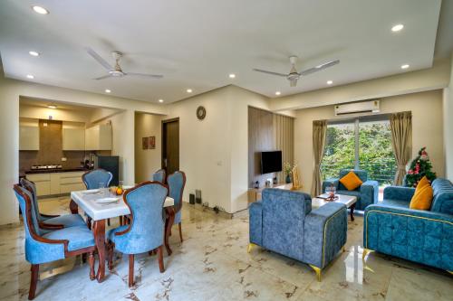 坎多林Premium 2BHK Apartment with pool at Candolim Beach的客厅配有蓝色的椅子和桌子