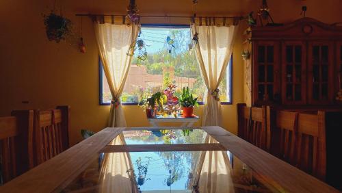 麦马拉Casa Munay的一间设有玻璃桌和窗户的用餐室