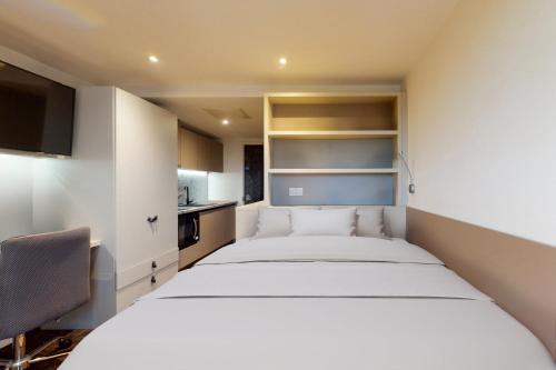 曼彻斯特Private Bedrooms with Shared Kitchen, Studios and 2 Bed Apartments at Canvas Manchester的卧室配有一张白色大床和一把椅子