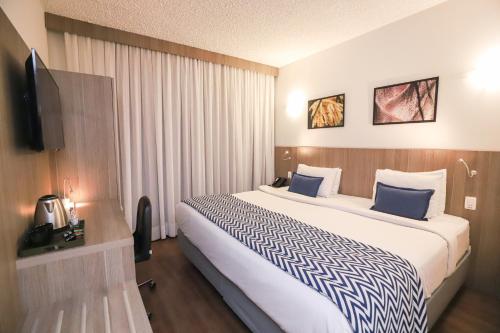 坎皮纳斯维拉科波斯机场华美达酒店的酒店客房设有一张大床和一台电视。
