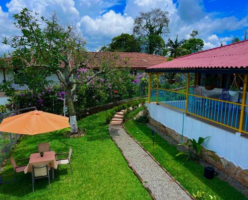 普韦布洛保Finca Hotel Mirador La Casona Quindio-Eje Cafetero的花园配有橙色遮阳伞和桌椅