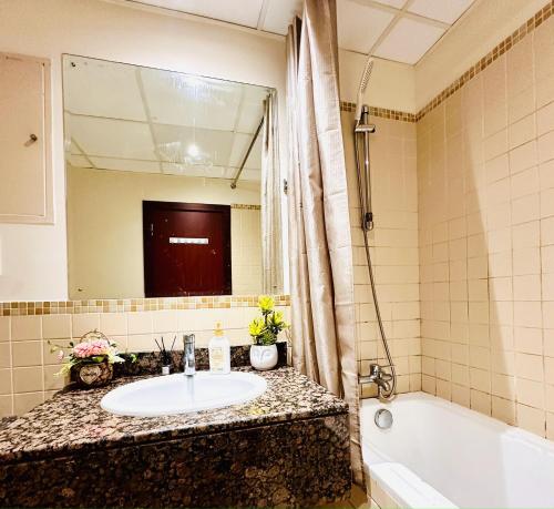 迪拜The Aero Hostel的一间带水槽、浴缸和镜子的浴室