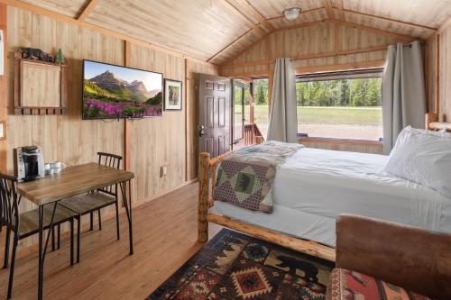 CoramSky Eco - Glacier General Store and Cabins的一间卧室配有一张床、一张桌子和一个窗户。