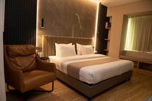 拉各斯Vertigo Hotel的一间卧室配有一张床和一把椅子